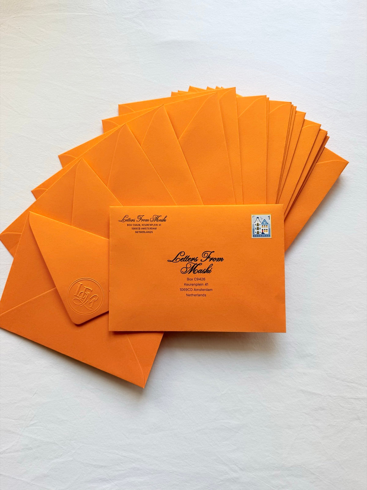 Orange Letters from Mashi envelopes with embossed wax-style seals, one addressed and ready to post